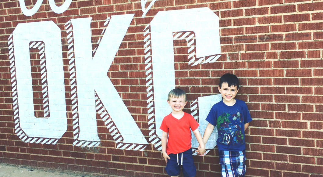 boys standing in front of OKC sign