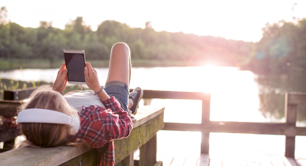 teen on phone laying on dock summer