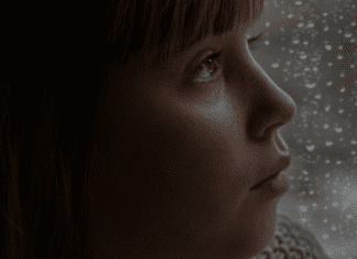 Child looking sad by rainy window