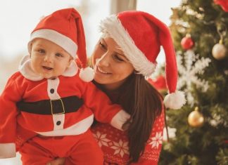mother and baby both dressed for Christmas; baby wearing Santa outfit and Mom in Santa hat