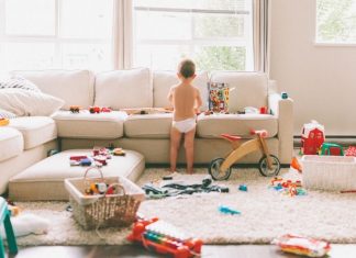 Messy living room, strewn with toys and a small child playing with them