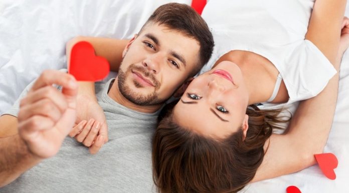 couple laying together holding hearts