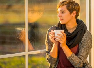 woman drinking coffee, looking out a window