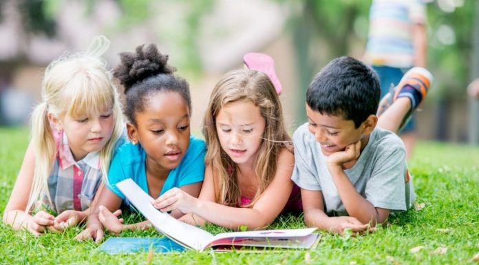 four young kids reading a book together