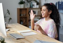 girl raising hand while looking at computer
