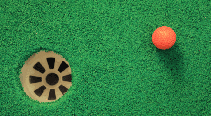 orange golf ball next to mini golf hole
