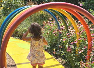 little girl walking through garden with rainbow arch