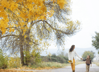 Woman and daughter walking outside amid yellow and orange fall foliage