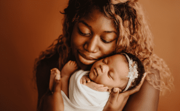 Black mom holding new baby, both with eyes closed.