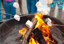Marshmallows being roasted over open flames outdoors.