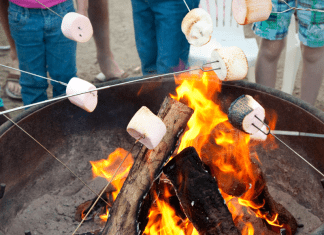 Marshmallows being roasted over open flames outdoors.