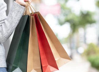 Tall mom shopping in gray sweater holding green, tan, red and another tan shopping bag,