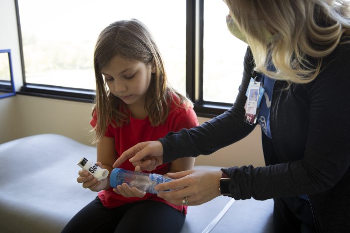 doctor helping girl with inhaler for asthma