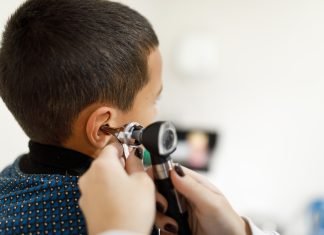 Doctor checking little boy's ears with an otoscope